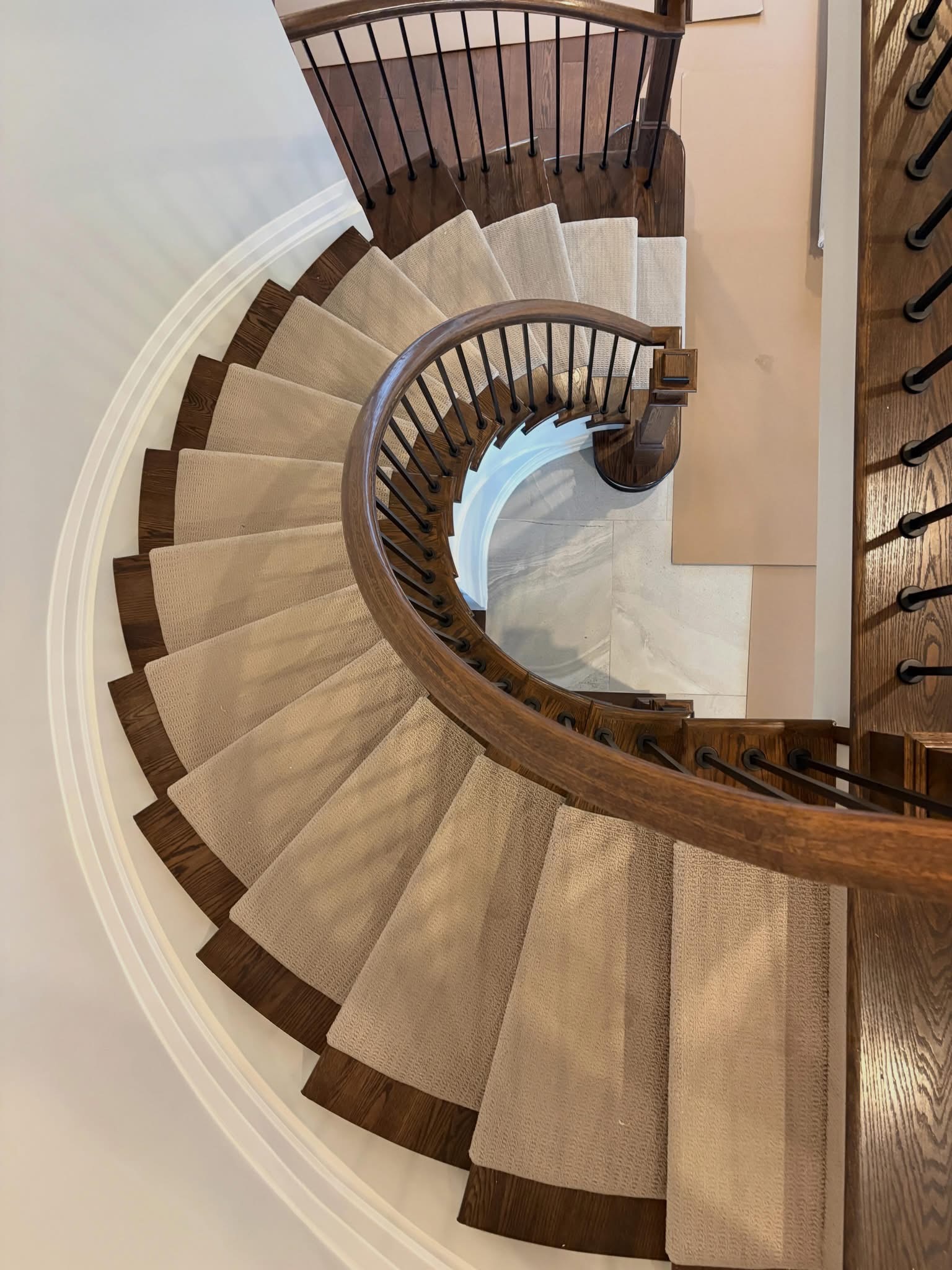 Curved staircase carpet installation with wood treads and dark railing